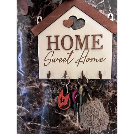 Koka atslēgu statīvs mājas formā ar uzrakstu “Home Sweet Home”, dekoratīvām sirdīm un četriem āķiem atslēgām.